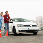 Instructor pointing at clipboard for student during driving lesson.
